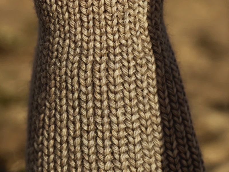Gros plan sur la maille d'une chaussette : fibres de laine et points visibles